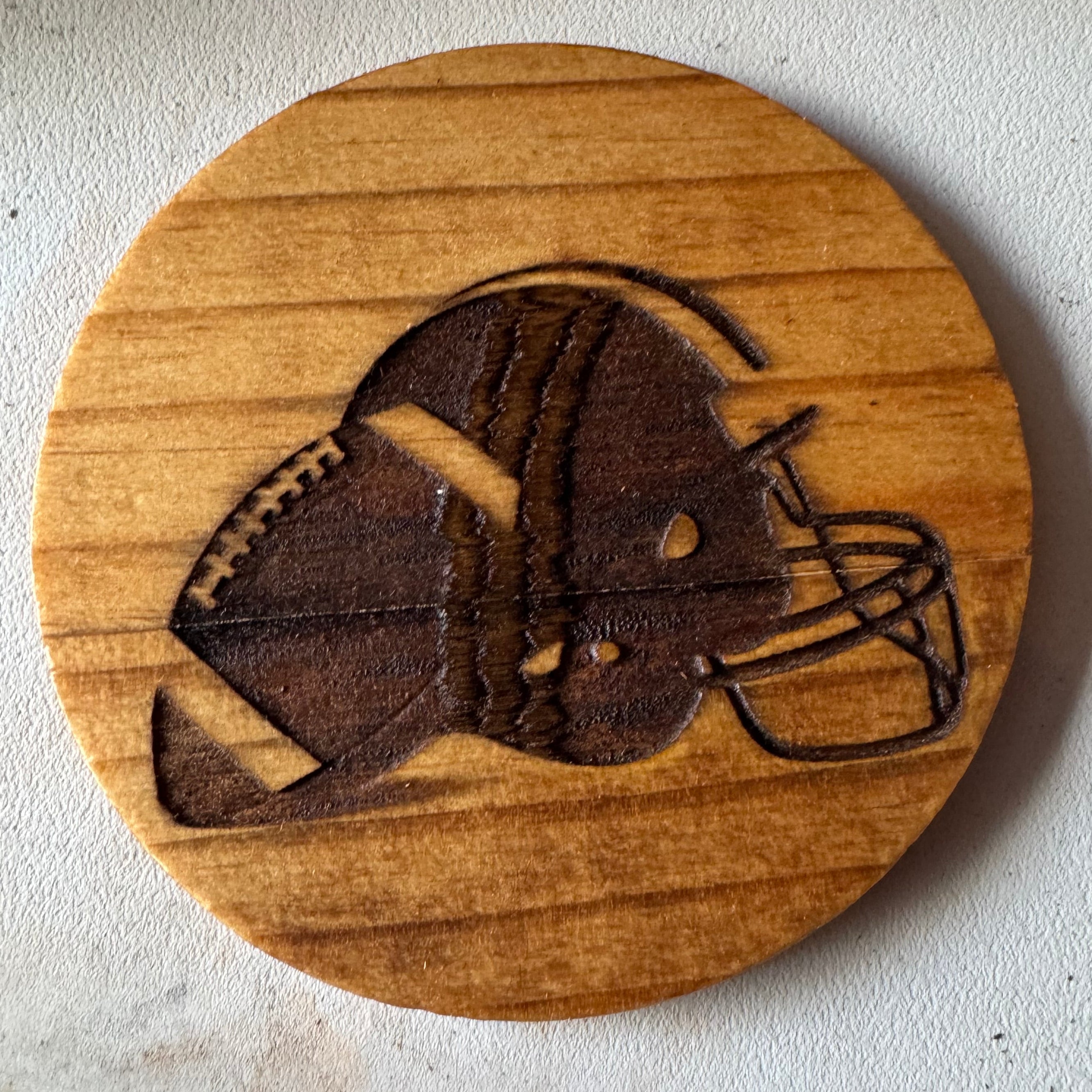 Wooden coaster with a laser-cut design of a football and helmet