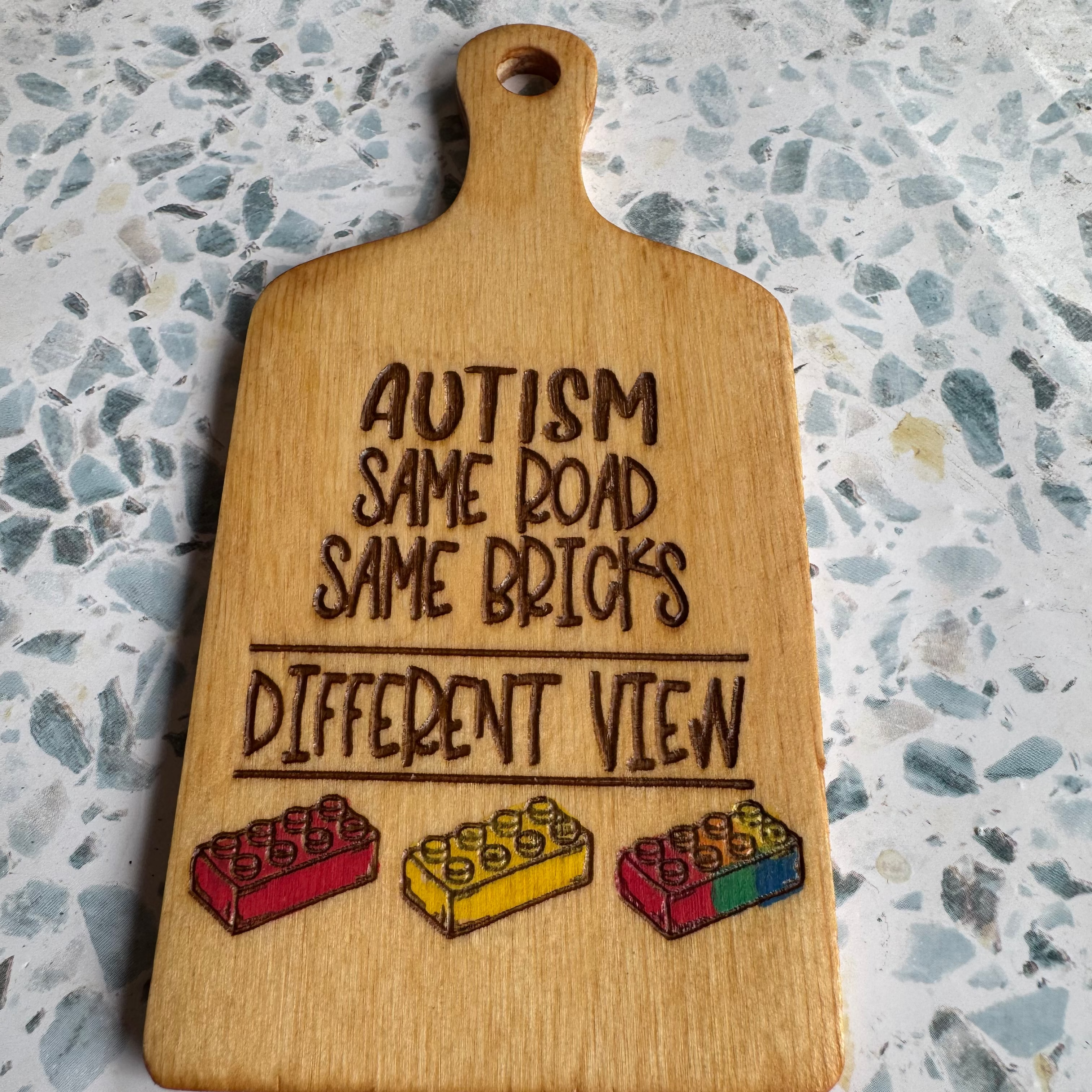6 inch paddle with engraved text and colorful blocks on a speckled countertop.